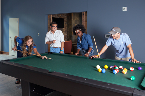 Students enjoy pool table in common room of dormitory