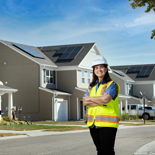 Woman in construction gear standing in front of a row of homes