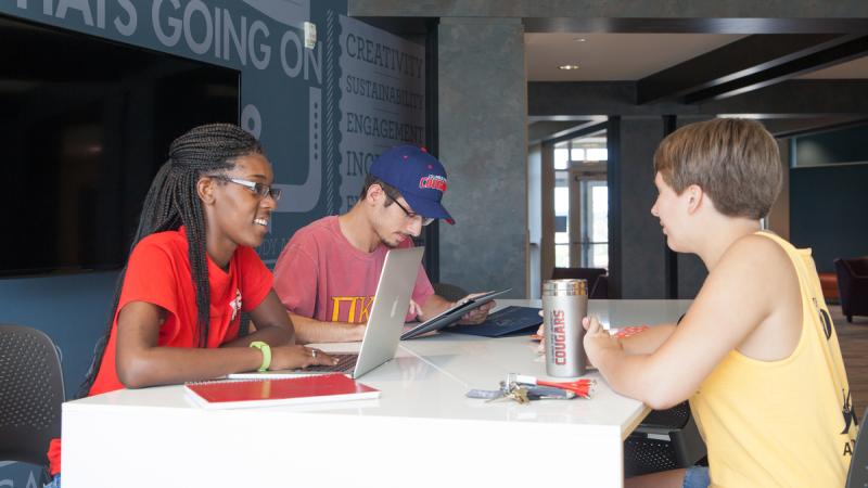 Three students sitting at a table and talking