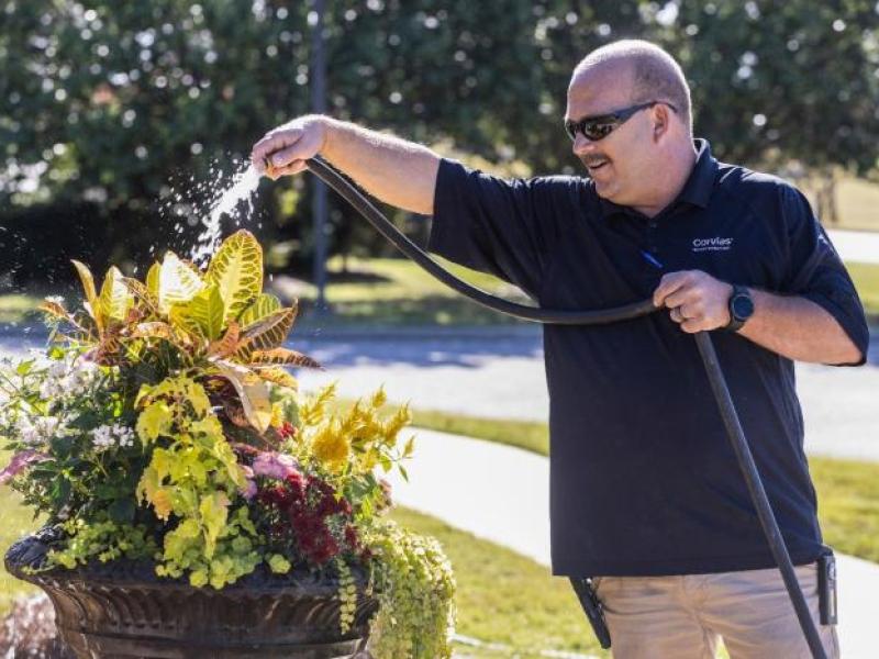 Corvias Property Management team member waters flowers